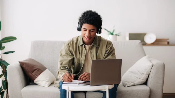 a man sitting on a couch using a laptop compute.