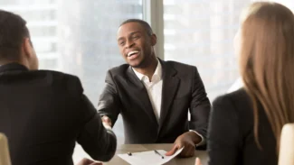 a man candidate sitting at a table talking to two colleagues