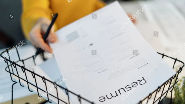 a person holding a pen and cv in a basket