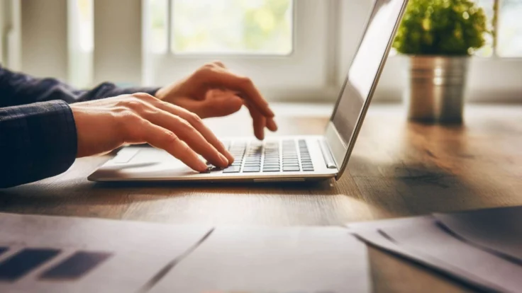 a person typing on a laptop on a table