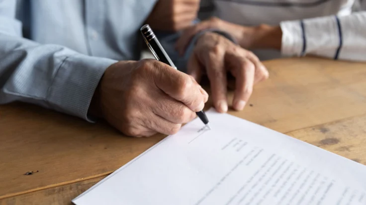 two people sitting at a table writing on a piece of paper