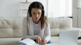 a woman sitting on a couch working on a laptop.