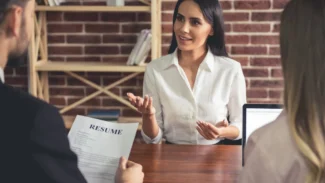 a woman having a job interview with two recruiters, a man and a woman, in front of a desk