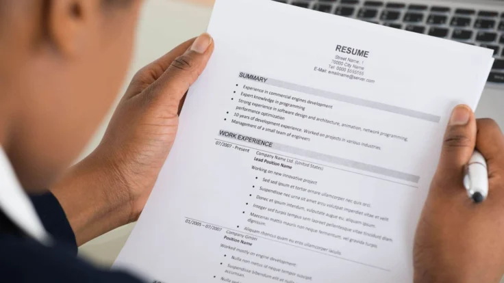a person holding a paper with a resume on it.