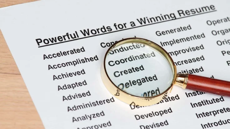 a magnifying glass sitting on top of a piece of paper with a list of powerful words for a cv