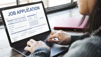 a woman working on a laptop with a job application on the screen.
