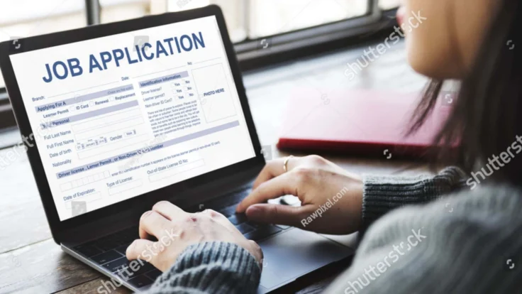 a woman working on a laptop with a job application on the screen.