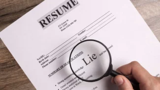 a person holding a magnifying glass over a resume.