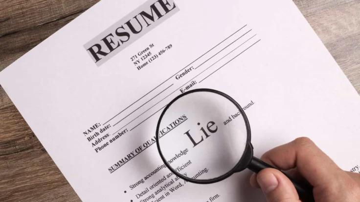 a person holding a magnifying glass over a resume.