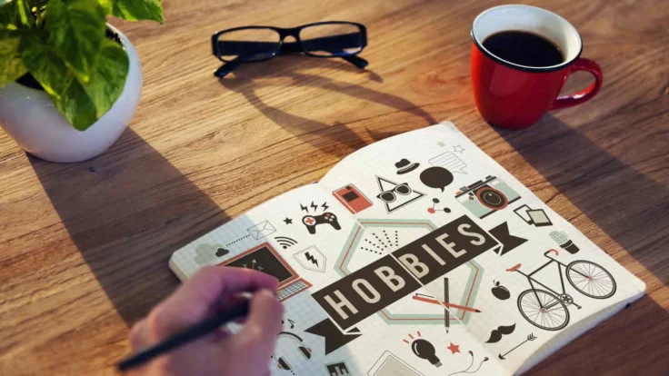 a person writing on a hobbies book with a cup of coffee next to it