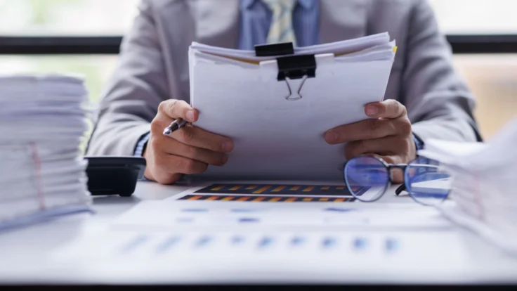 a man sitting at a desk holding a binder