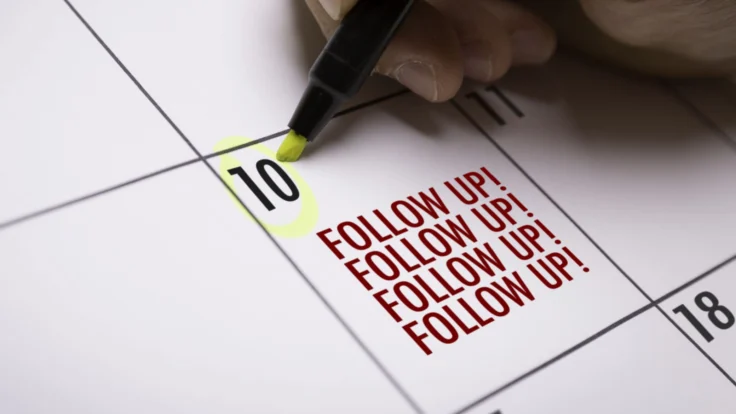 a person writing on a calendar with a marker.