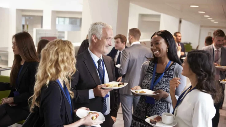 a group of people standing around eating food.