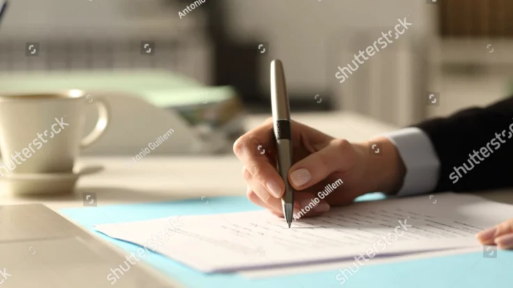 a person writing on a piece of paper with a pen