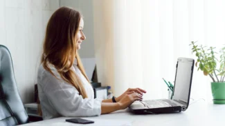 a woman sitting at a desk using a laptop computer.