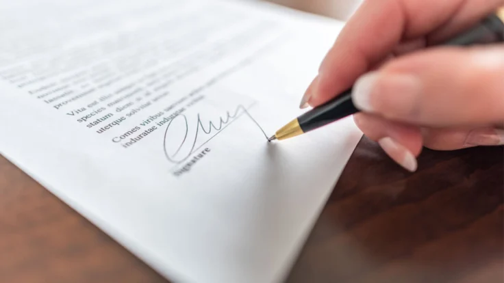 a person writing on a piece of paper with a pen.