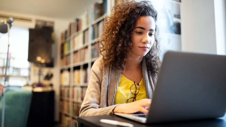 student writing in her laptop